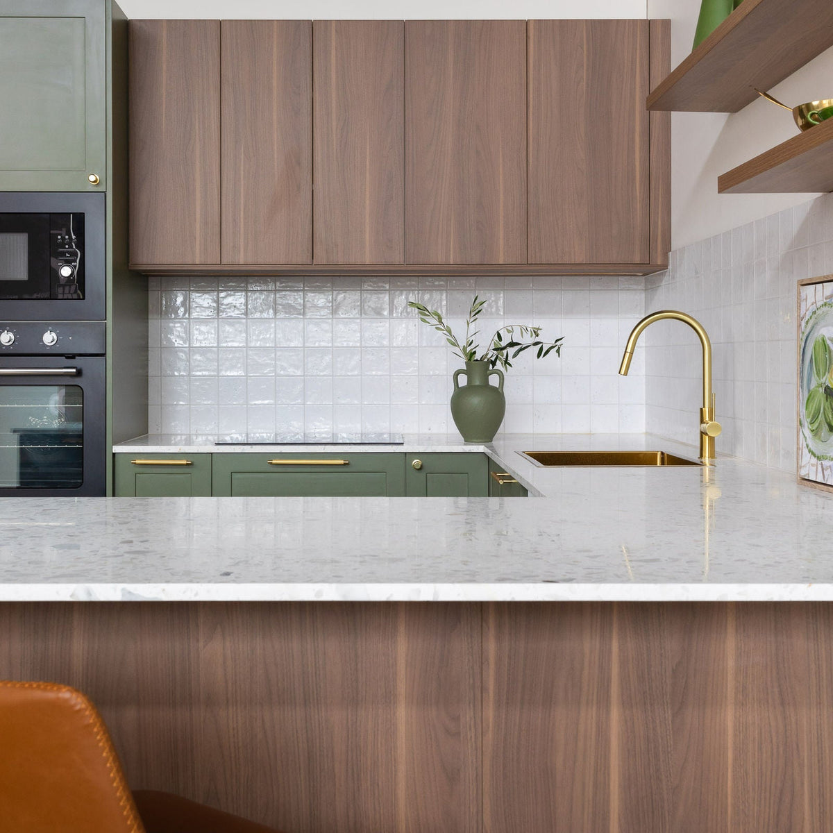 Kitchen with walnut woodgrain laminate wall cabinets and island panel above green base cabinets with brass handles
