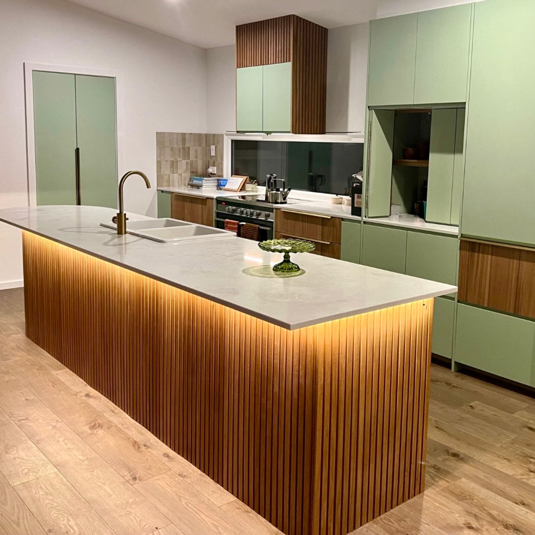IKEA METOD kitchen with sage green Finger Pull doors, a timber-slatted island lit from below and a stone benchtop