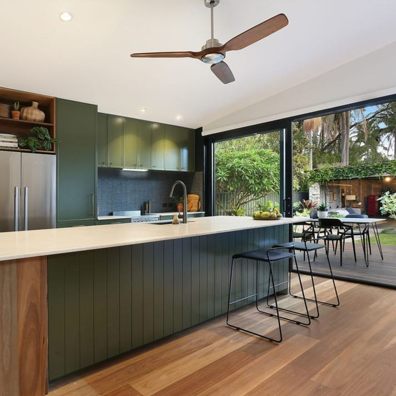 Kitchen with deep green painted Slim Shaker and Coastal profile doors in Dulux Algae, a grooved island and a stone benchtop