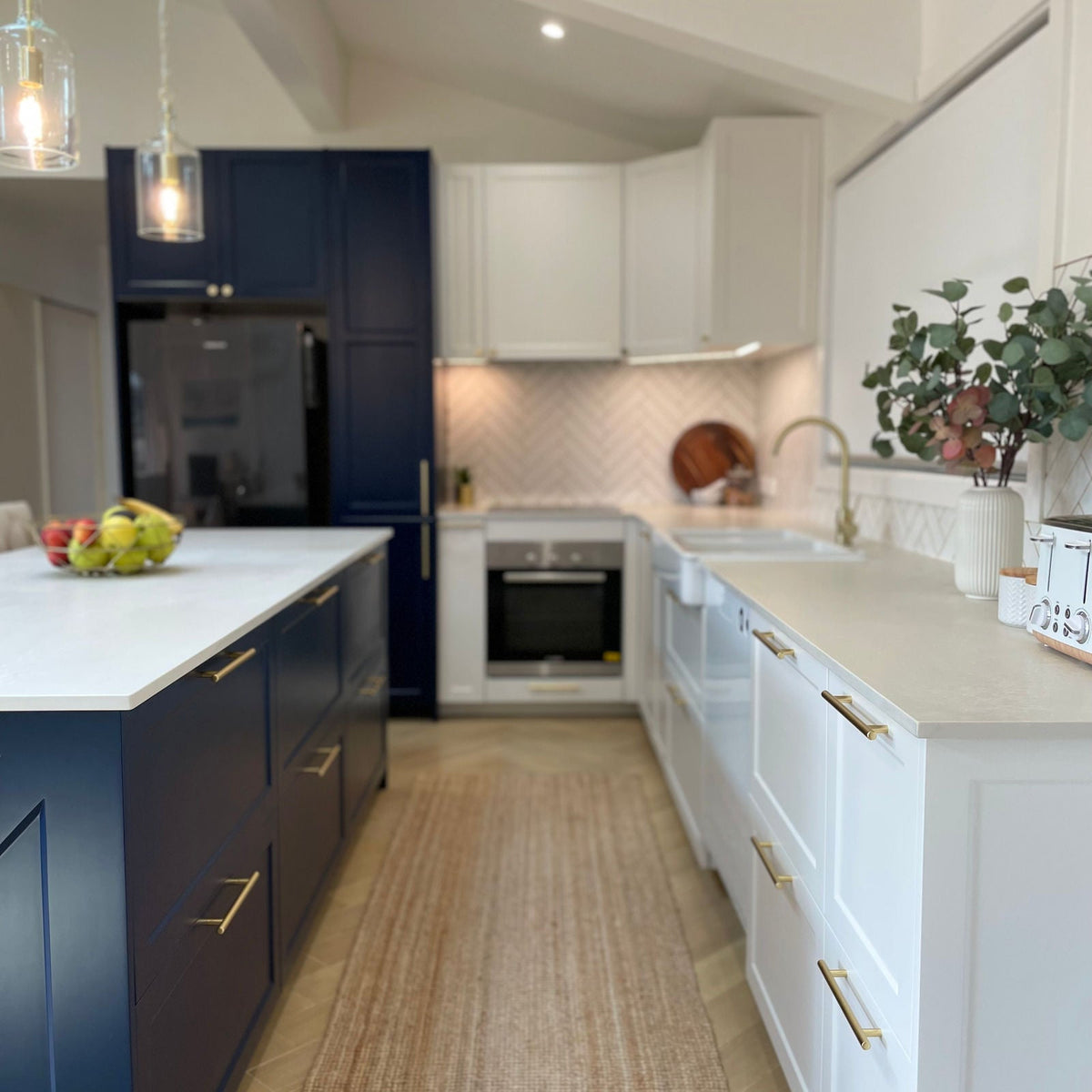 Kitchen with navy French Shaker tall and island cabinets beside white French Shaker base cabinets