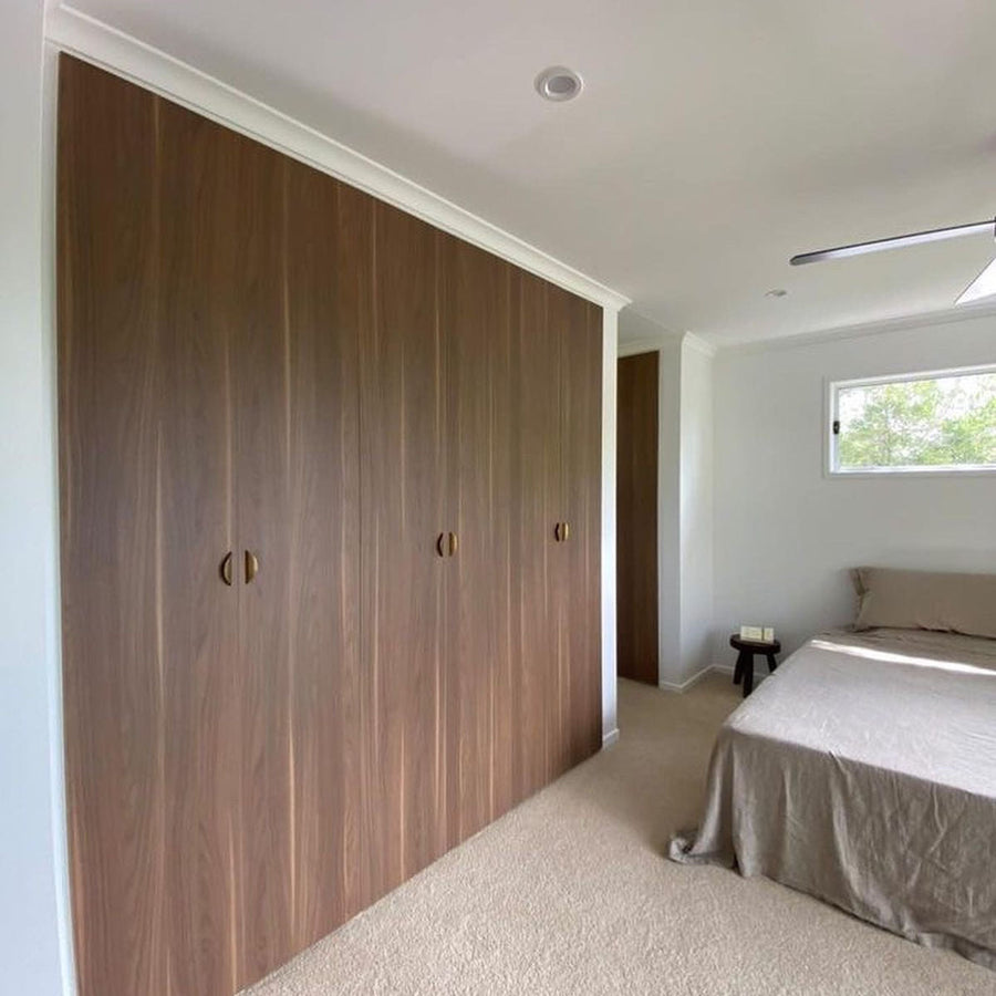 Wall of IKEA PAX wardrobes with full-height walnut woodgrain laminate doors in a bedroom