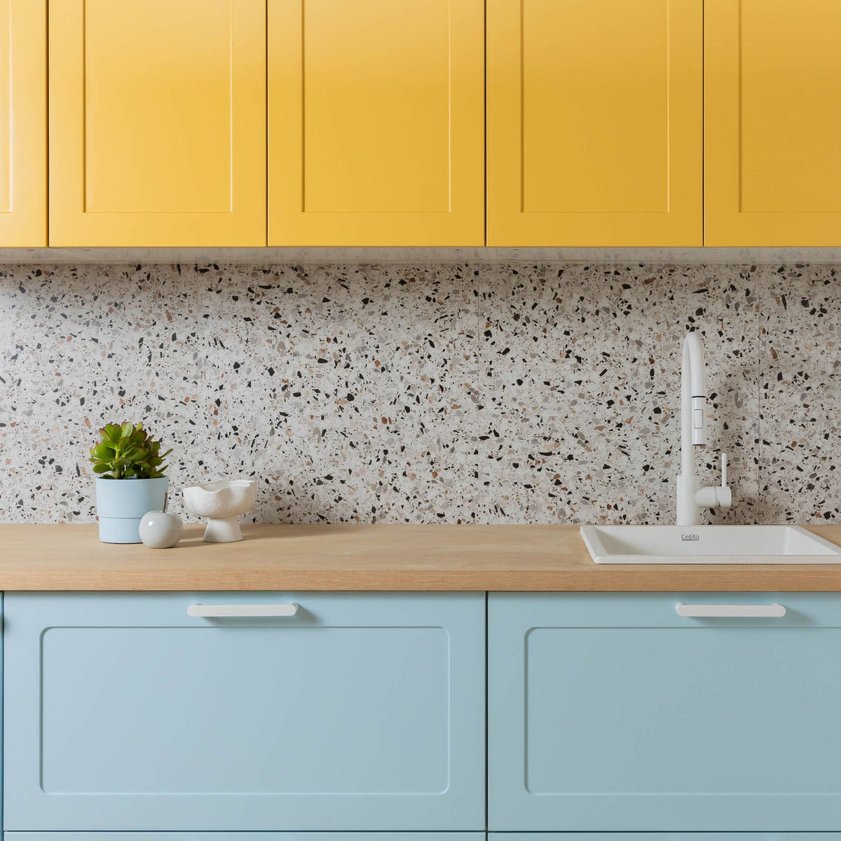 Display kitchen with yellow Round Shaker wall cabinets above pale blue Round Shaker base cabinets, a timber benchtop and a terrazzo splashback
