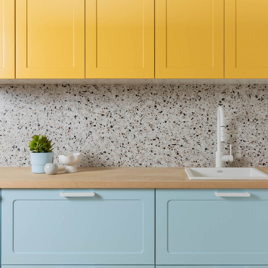 Display kitchen with yellow Round Shaker wall cabinets above pale blue Round Shaker base cabinets, a timber benchtop and a terrazzo splashback
